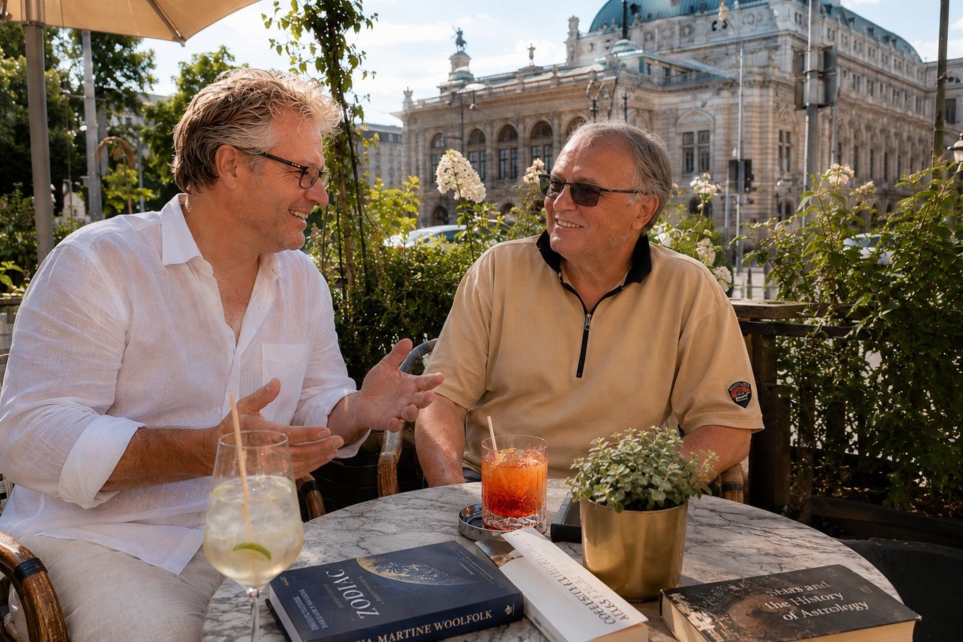 Radim Kaufmann in a crisp white linen shirt with sleeves rolled to the elbows sitting on the back terrace of a Vienna Ringstrasse cafe on the first warm afternoon of June, opposite his friend Bernhard Mann in a beige polo shirt mid-sentence about the precession of the equinoxes, the marble cafe table between them with an Aperol Spritz and a Hugo and three illustrated books on the history of astrology including Zodiac by Martine Woolfolk and Stars and the History of Astrology, the rose garden of the cafe terrace, the classical facade of the Burgtheater on the Universitatsring rising behind the trees in the background with its characteristic green-copper dome and crowning statue, late afternoon sun filtering through the foliage, two friends in an unhurried Vienna conversation